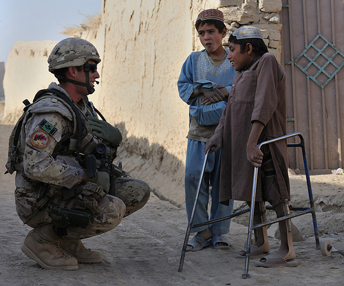 07 November 2009-Kandahar,Afghanistan Since the road improvement project in the village of Deh-e Bagh, a young Afghan boy stricken with Polio has greater mobility allowing him access to the road to greet Lieutenant Pierre-Vincent Daigle as he passes through the village on a patrol. Photo by Master Corporal Angela Abbey, Canadian Forces Combat Camera